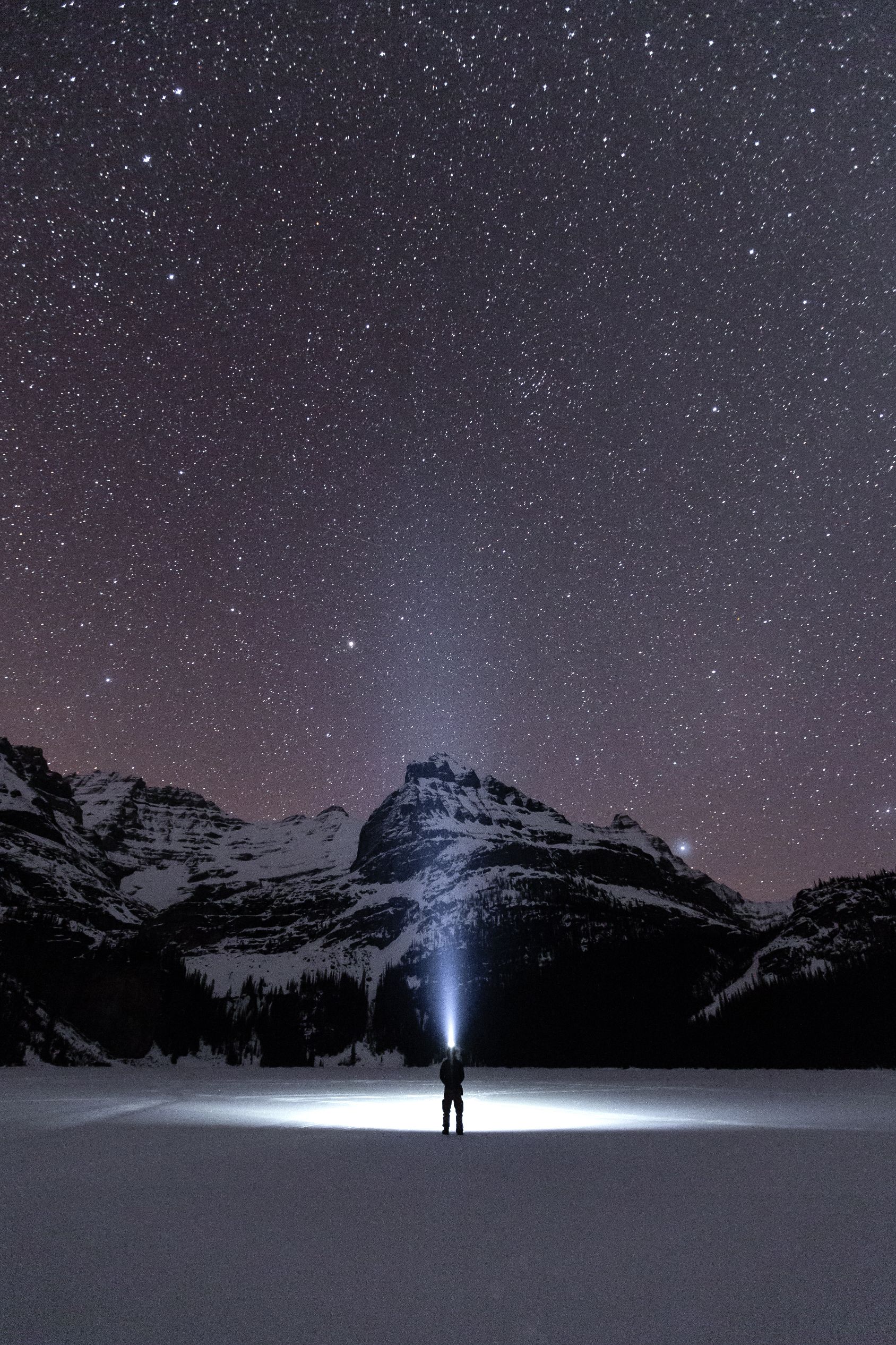 Man at night with head torch looking up at stars. 
