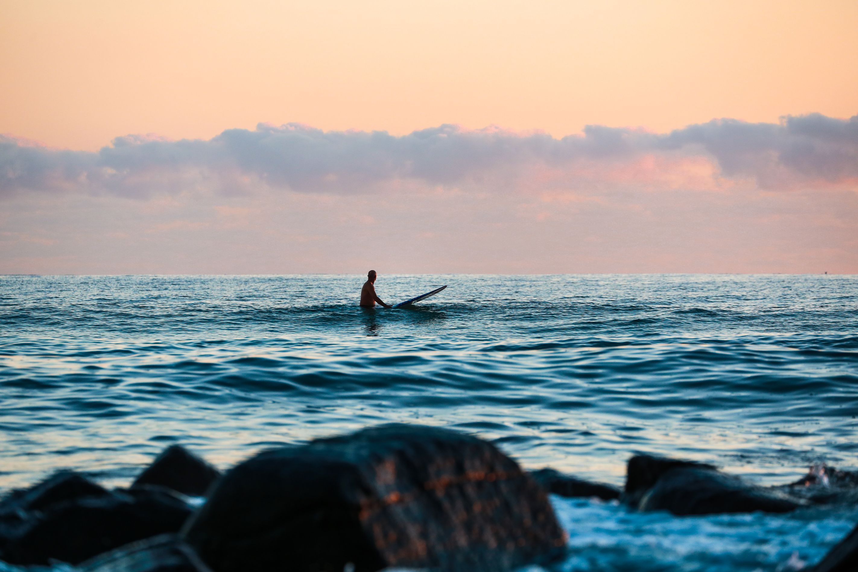Surfer waiting in the water for a wave at sunset. 
