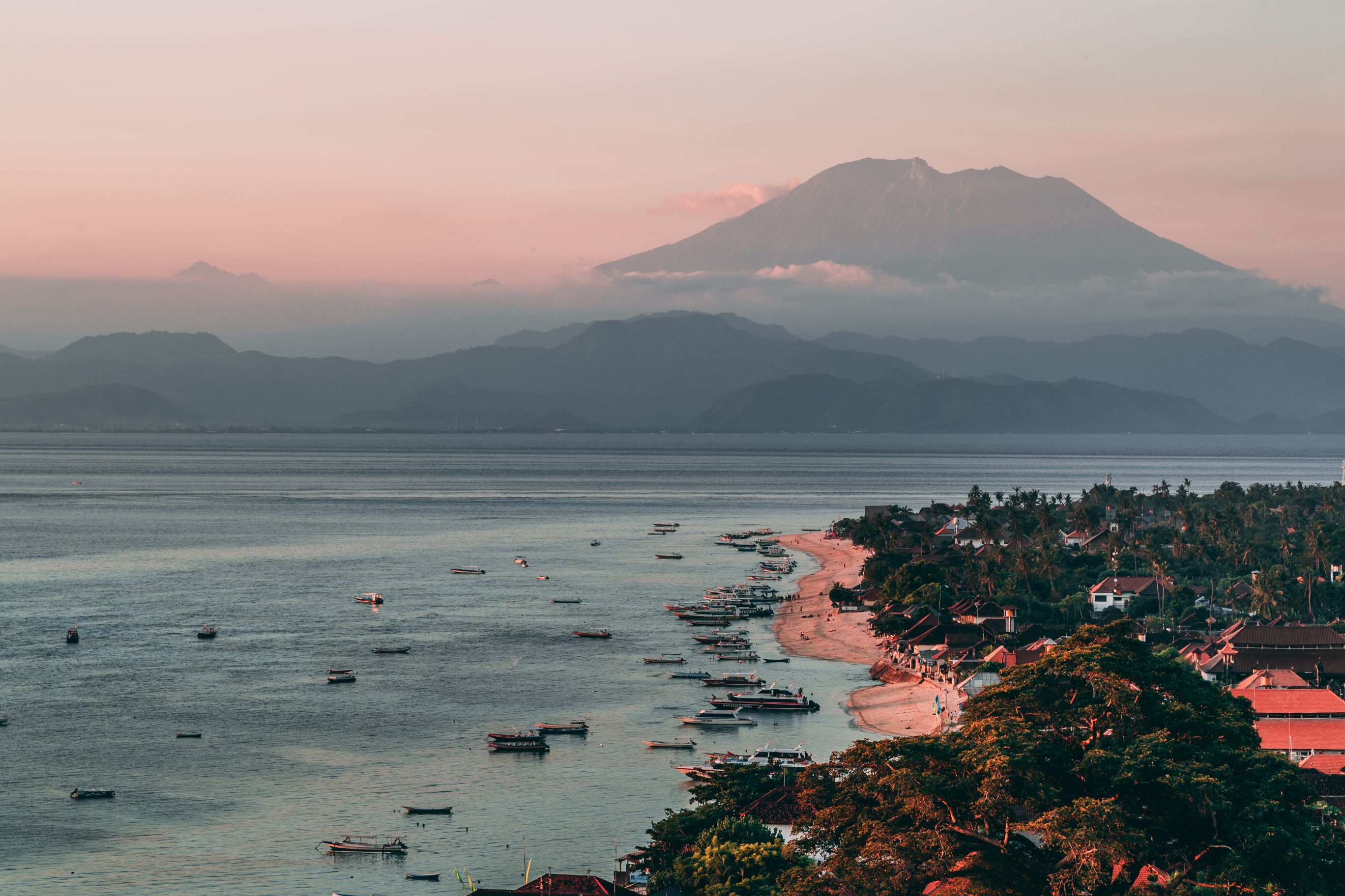 Sunset over a balinese beach, village and fishing boats. 