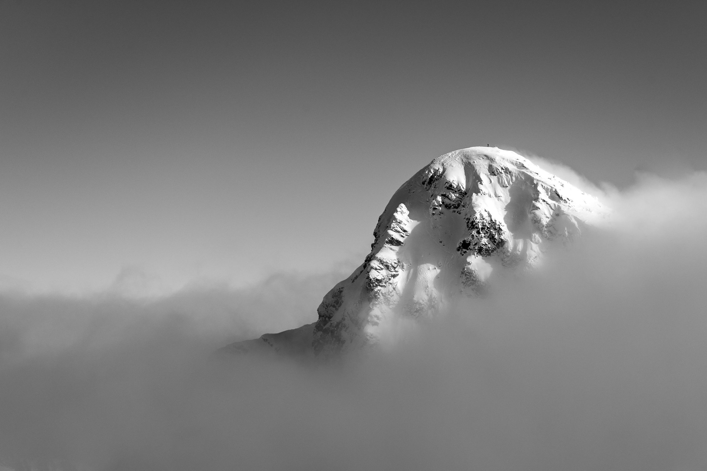 Black and white mountain peak above the clouds. 