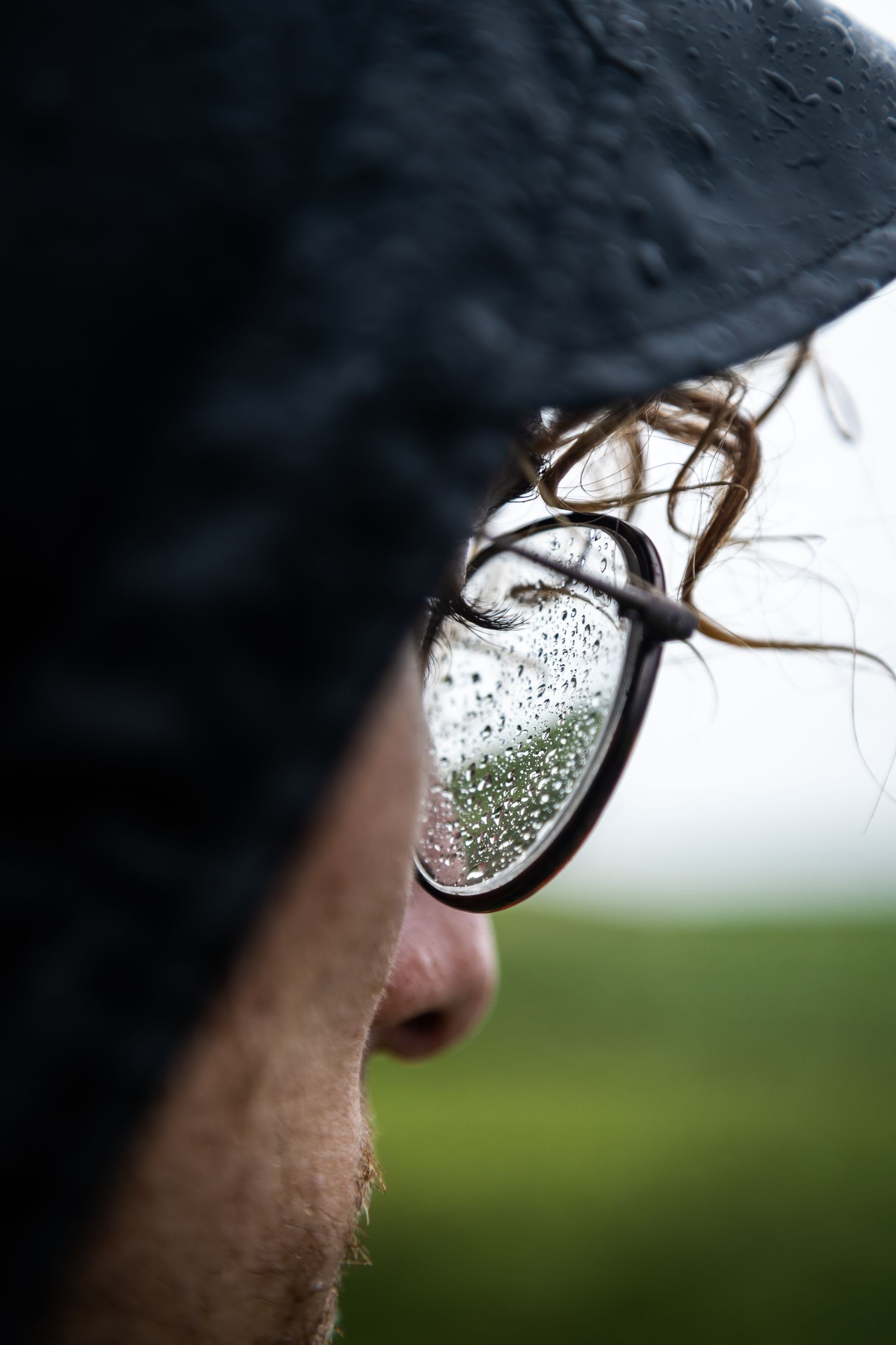 Side profile of man with rain jacket on and glasses. 